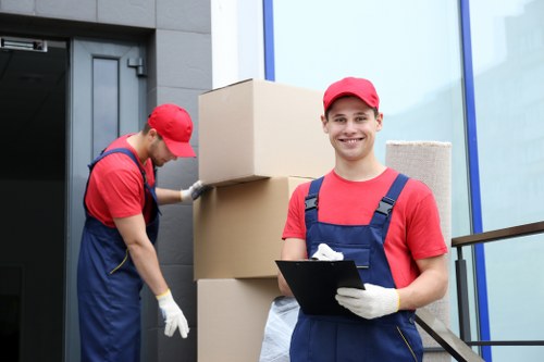 Professional movers handling furniture on a residential street in New Cross